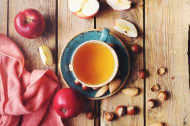 Sıcak sonbahar kompozisyonu bir fincan çay, taze elmalar ve fındıklar kırsal ahşap masa, üst manzara, seçici odak