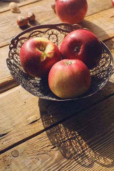 Cozy morning autumn composition fresh organic apples in vintage vase on rustic wooden table, selective focus