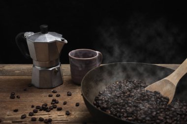 Ahşap masa üstüne pirinç pan ve cezve tahta kaşıkla kavrulmuş kahve çekirdekleri 