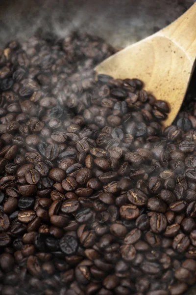 Ahşap masa üstüne kavrulmuş kahve çekirdekleri pirinç tahta kaşıkla pan 