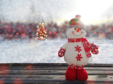 çelenk ışıkları ile arka planda kök narin ağacı ile noel kardan adam dekor