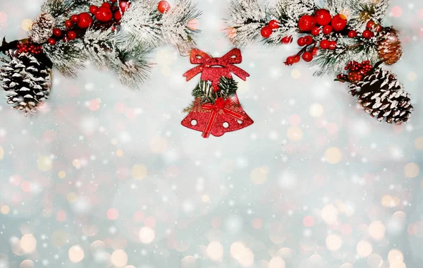 Kerstklok op dennenboom tak met kegels en sneeuw op blauw — Stockfoto