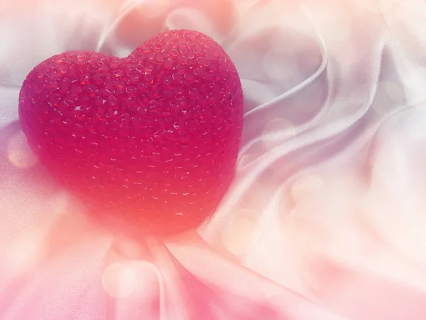 Rött hjärta på silkeslena tyg material alla hjärtans dag bakgrund — Stockfoto