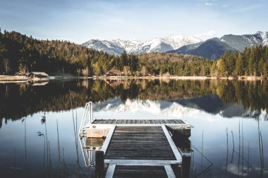 Tahta köprü, yakındaki dağların ve ormanların yansıtıldığı berrak bir göle açılıyor..