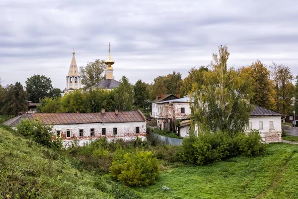 View of old historical town Suzdal from the earthen wall on cloudy day in autumn. Belfry, golden dome of the church, old brick building. Russia.