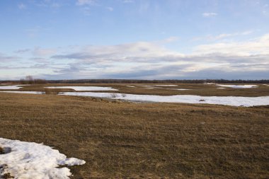Güneşli bahar günü kar kalıntıları ile sonsuz düz çayır