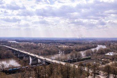 İlkbaharda demiryolu, üstgeçit, nehir ve gökyüzü ile doğal peyzaj