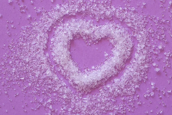 White sea salt crystals heart on a purple background