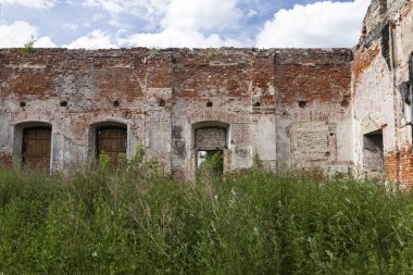 Eski bir yıkılmış bina ve yeşil çim tuğla duvar.