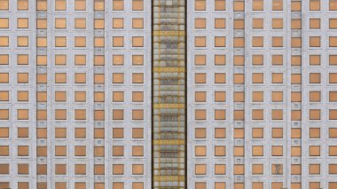 Düz bina cephesi, gri duvar, altın kare pencereler, ön görünüm