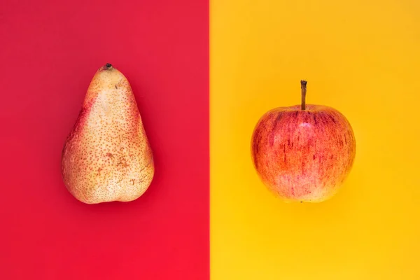 Pear vs Apple. Juicy yellow pear and fresh red apple top view close up
