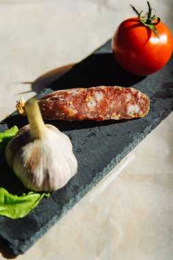 sosis sarımsak ve domates karanlık taş plaka üzerinde 