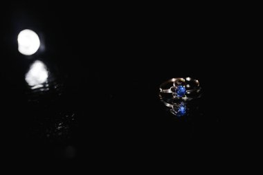 Koyu arka plan üzerinde mavi elmas yüzükle.