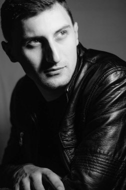 Siyah ve beyaz deri ceket bir adam portresi.