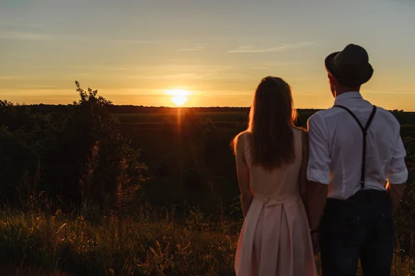 一个年轻的男人和女人站在一起 看着从后面拍摄的日落 — 图库照片
