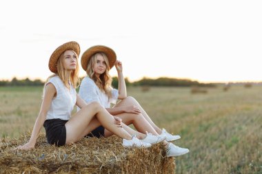 Samanlık üzerinde oturan ve uzağa bakarak hasır şapka genç kız