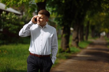 Genç adam parkta akıllı telefondan konuşuyor.