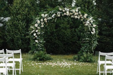 Ağaçların arka planında beyaz çiçekler ile Düğün ark