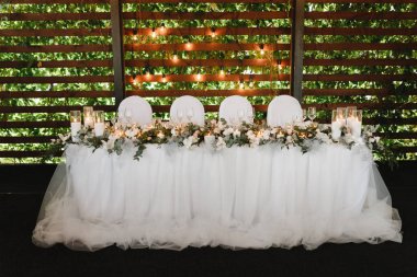 Beyaz çiçekler ve mumlar ile süslenmiş 4 kişilik düğün masası