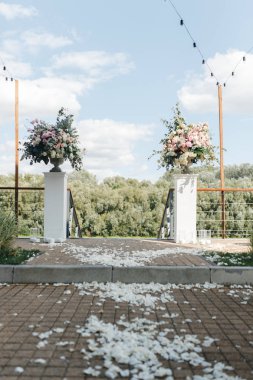 Bir düğün dekorasyonu olarak çiçeklerle sütunlar için yolda Yaprakları