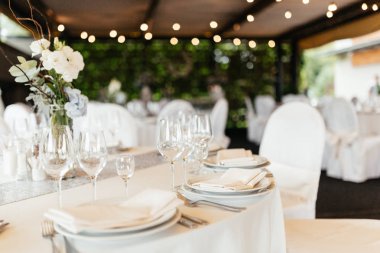 Restoranda zarif masa ayarı. Şarap bardakları ve peçete ile beyaz tabaklar