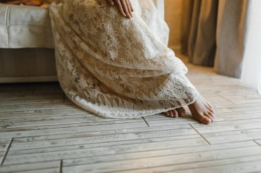 Gelin ellerini gelinliğin üzerinde tutuyor.