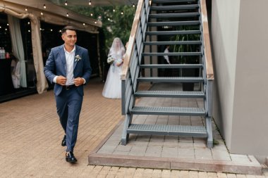 Koyu takım elbiseli mutlu damat düğün törenine gidiyor. Yeni evlilerin portresi. Düğün fotoğrafçılığı