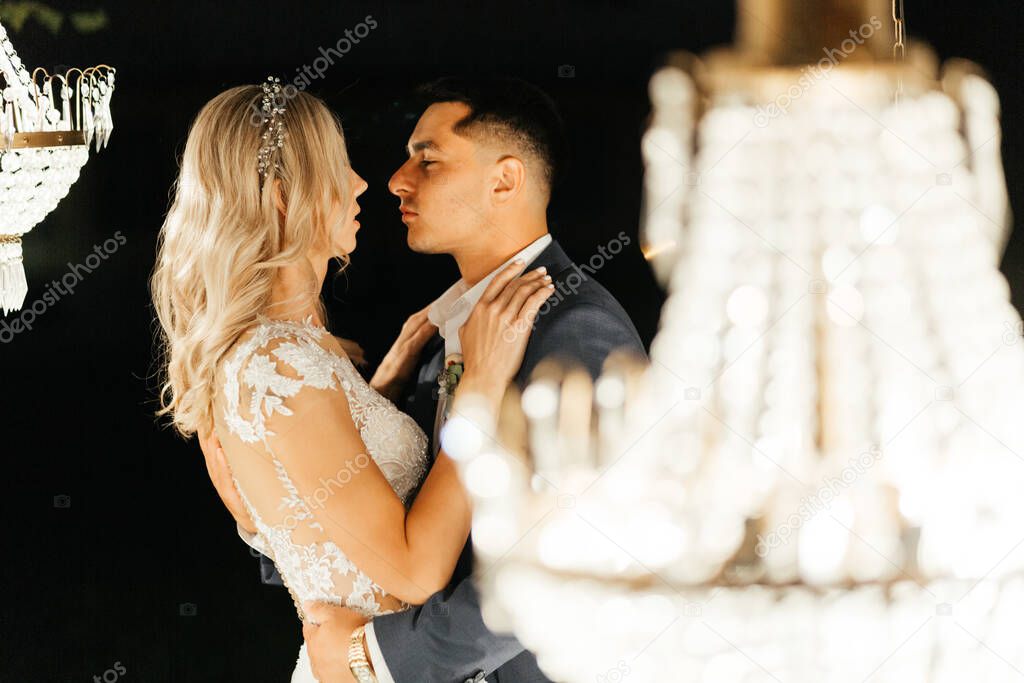 Happy newlywed standing in the lights of chandelier. The moment before kissing. The end of the wedding day. Newlywed portrait. Wedding photography