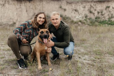  Gülümseyen adam ve kadın doğada köpeklerinin yanında oturuyorlar. Aşk hikayesi. Erkek ve kadın portresi