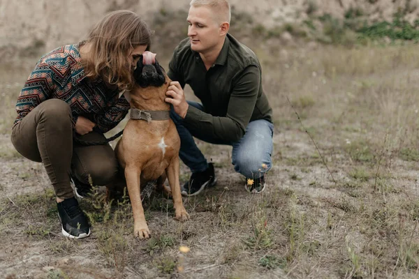 Couple in love petting their dog in nature. Love story. Man and woman portrait