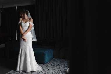 Dantelli gelinlik ve duvak giymiş, başı omuzuna yaslanmış bir şekilde odada duran hassas gelin. Gelin portresi. Kadın portresi