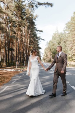 Gelin ve damat ormanda el ele tutuşarak yollara düşüyorlar. Gelin ve damat portresi. Düğün fotoğrafçılığı