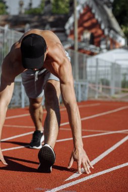 Yarış pistinde egzersiz yapan kaslı bir adam. Adam kaçmaya hazırlanıyor. Sporcu. Güçlü bir sporcu.