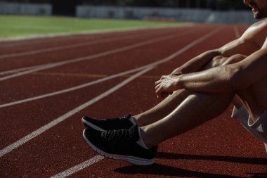 Erkek bacakları. Atlete pistte oturuyor. Sporcu. Güçlü adam.