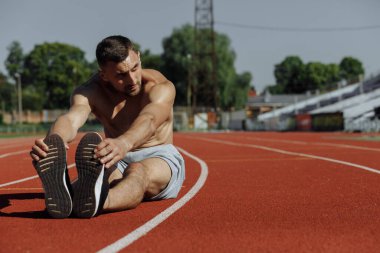 Hipodromda idmandan sonra esneme hareketleri yapan gömleksiz bir adam. Sporcu. Güçlü adam.