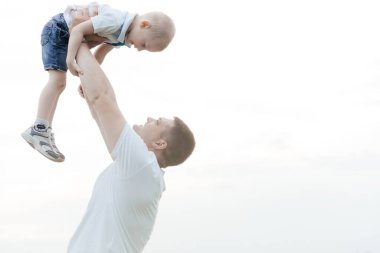 Baba, oğlunu elleriyle gökyüzüne fırlatıyor. Baba ve oğul. Mutlu aile