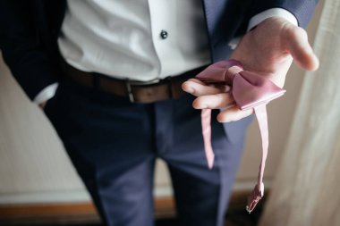 Erkek el pembe papyon tutuyor. Düğün adamı aksesuarları. Takım elbiseli adam.