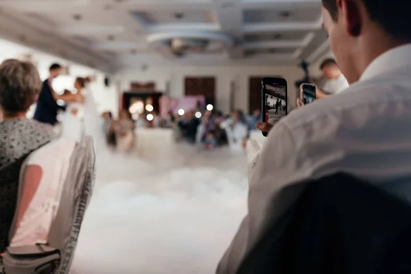 Nierozpoznawalny mężczyzna robiący zdjęcia pierwszym nowożeńcom tańczącym przez telefon — Zdjęcie stockowe