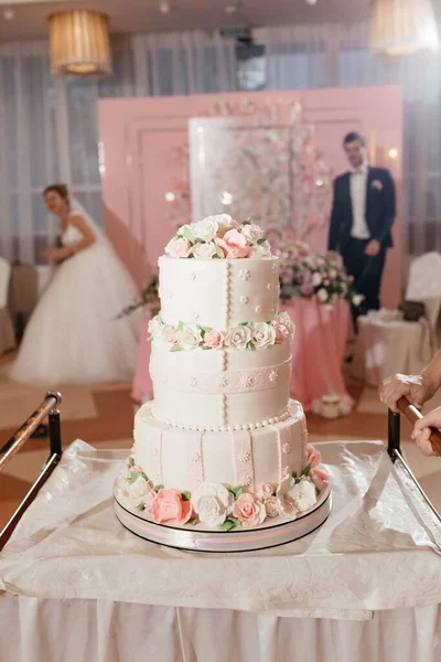 Pastel de boda decorado con rosas cremosas en el fondo de la novia y el novio — Foto de Stock