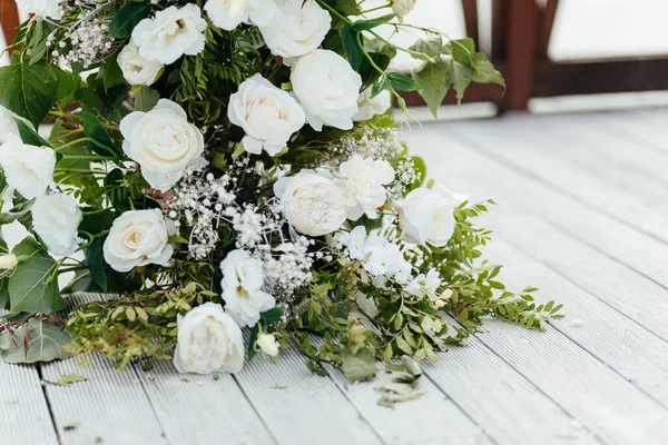 Beyaz ahşap arka planda bir buket beyaz gül ve yeşillik. Düğün kemeri. Düğün yeri. — Stok fotoğraf