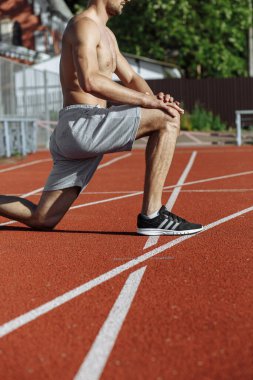 Koşmadan önce yarış pistinde kaslı bir adam esniyordu. Yan görüş. Sporcu. Güçlü adam.