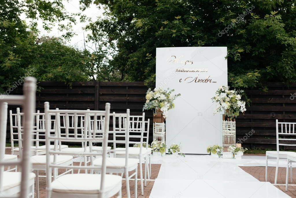 Outside wedding ceremony. White wedding arc and chairs for guest