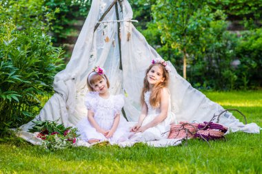 Beyaz elbiseler iki kız kardeş açık beyaz Boho çadır oturmak. 