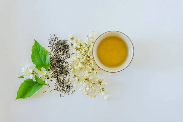 Tazza di tè, tè verde, fiori secchi di gelsomino e rametto di ja — Foto Stock