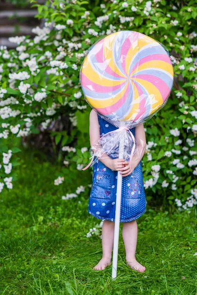 4 years old girl hide behind the big lollypop. Photo session in — Stock Photo, Image