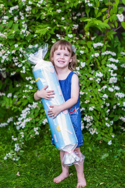 4岁的女孩拿着大糖果。花园里的夏天. — 图库照片