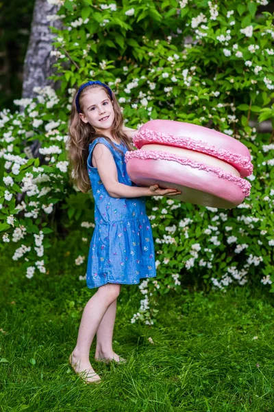 8岁的女孩拿着大马卡龙。夏季派对户外. — 图库照片