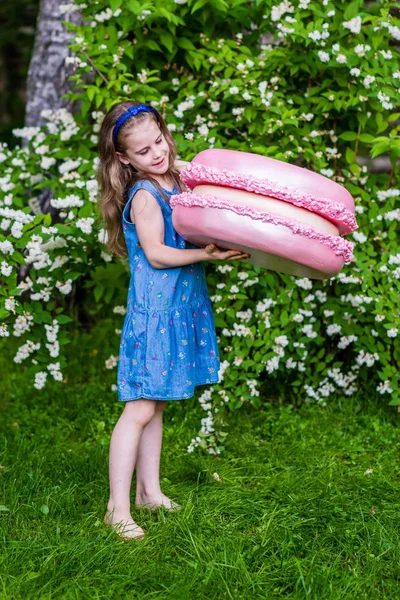 8 years old girl look to the big macarons. Summer party outdoor. — Stock Photo, Image