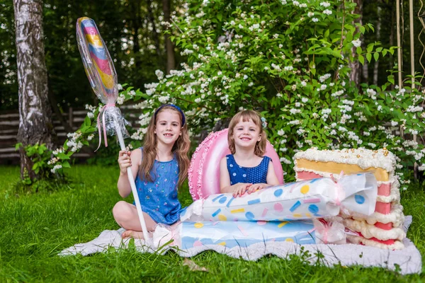 Dvě děvčata s falešnými sladkostmi. Fotografická zóna v zahradě. — Stock fotografie