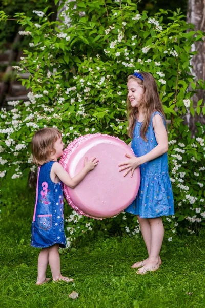 两个小个子的女孩拿着大马卡龙。夏季派对户外. — 图库照片